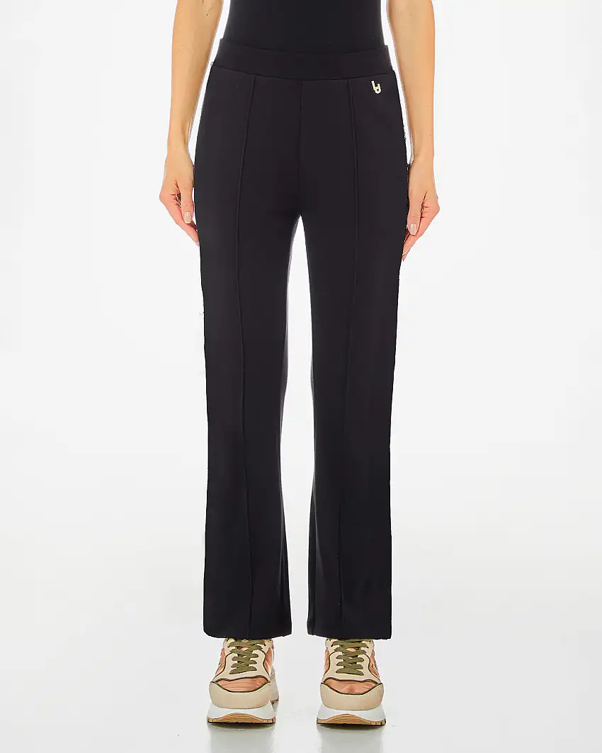Pantaloni a trombetta neri in jersey con piega frontale cucita e placca logo dorata con strass sul fianco