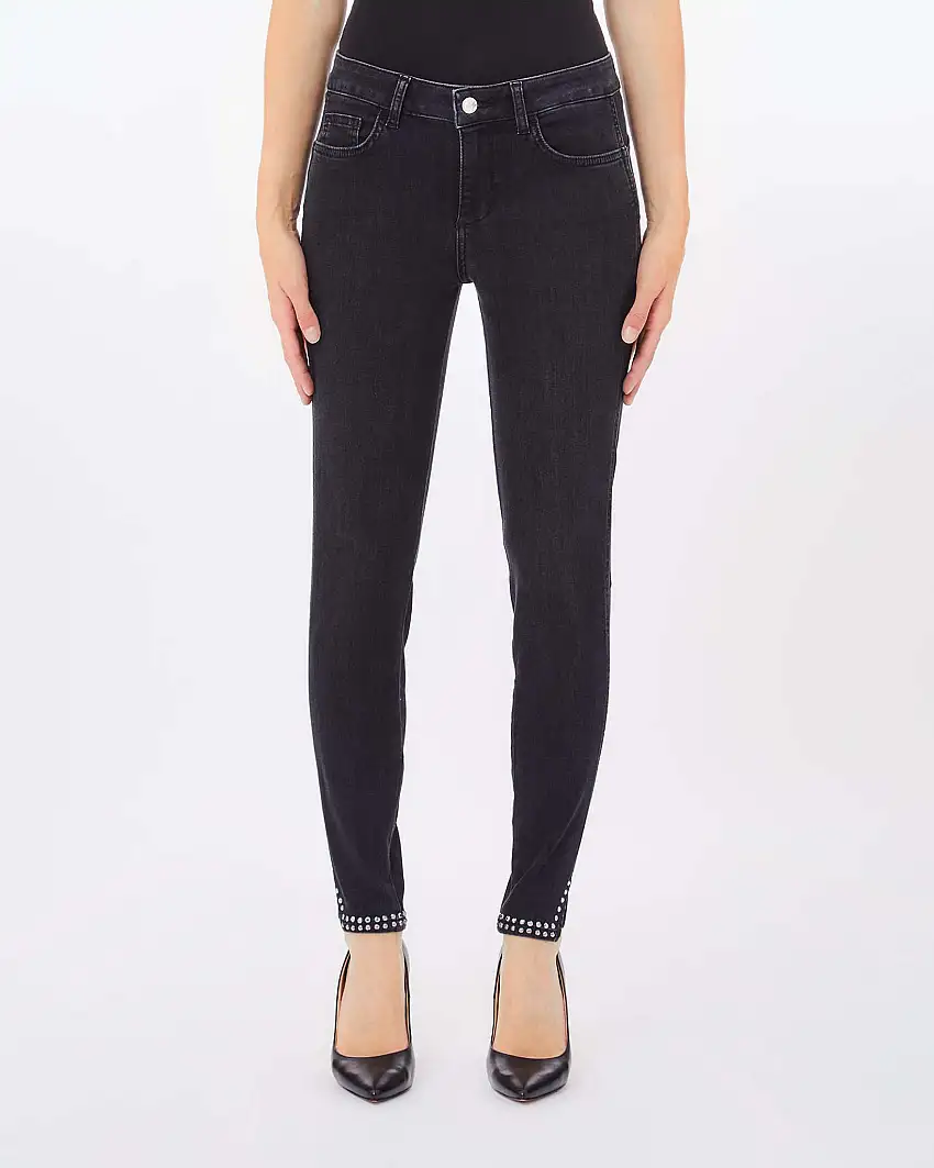 Jeans skinny nero lavato a vita media in cotone stretch con spacchetti laterali e borchie applicate al fondo